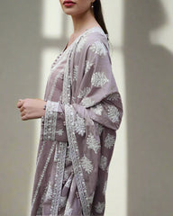 Woman wearing a light purple traditional outfit with white floral embroidery against a neutral background