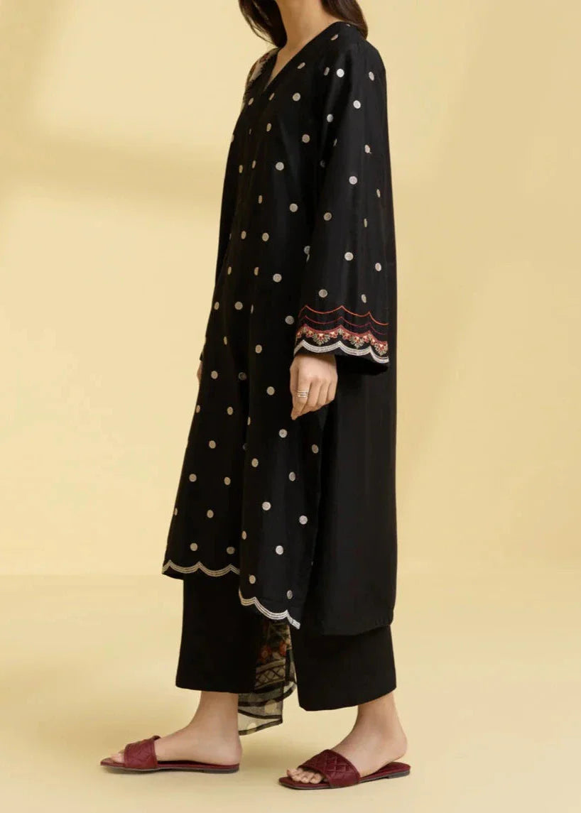 Woman wearing a black dress with white polka dots and embroidery on a beige background