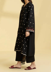 Woman wearing a black dress with white polka dots and embroidery on a beige background